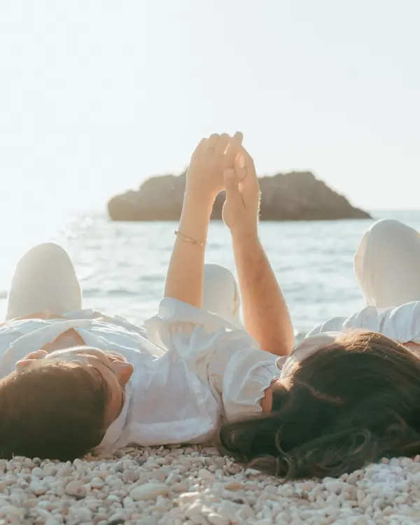 Couple in white holding hands by the sea